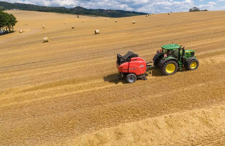Overview of a VB 7190 baler in a straw field with round bales under a nice sky