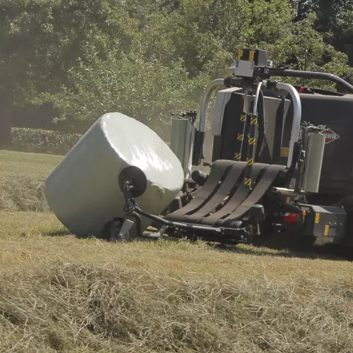 Turning bales at a flat side after wrapping